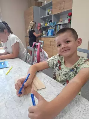 Chłopczyk mazakiem maluje obrazek dla taty.