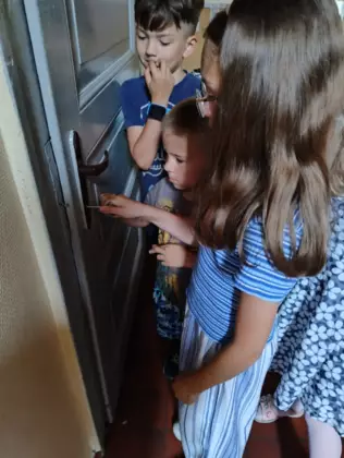 Dzieci otwierają drzwi kluczem.