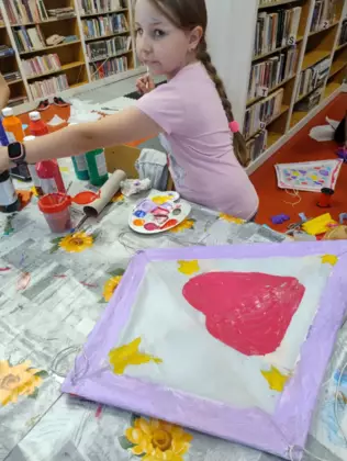 Dziewczynka maluje farbami latawca.