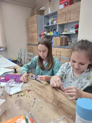 Dziewczyny nawijają korale na sznurek.