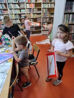 Dzieci malują farbami latawce.