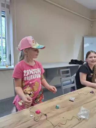 Dziewczynka nawija na sznurek korale dla mamy.