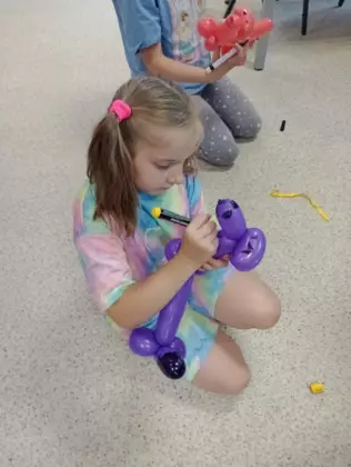 Dziewczynka dopracowuje swojego balonika w kształcie pieska.