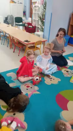 Dzieci siedzą na dywanie i zgadują zgadywanki.