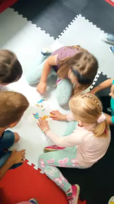 Dzieci układają puzzle na dywanie.