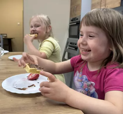 Dzieci jedzą gofry z bitą śmietaną i owocami
