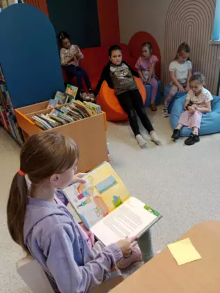 Dziewczynka czyta fragment z książki pt. Na ostatni guzik, Jana Twardowskiego.