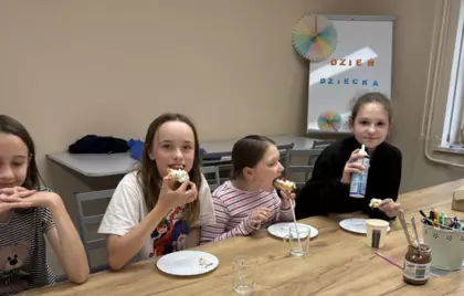 Dzieci jedzą gofry z bitą śmietaną i owocami.