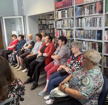 Seniorzy w bibliotece słuchający Pana Kotysia.