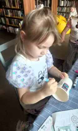 Dziewczynka dekoruje swój tradycyjny wiatrak wykonany z kubeczka.