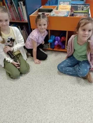 Dzieci ulokowały balonowe pieski w regale z książkami.