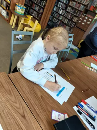 Dziewczynka rozwiązuje kodowanke na kartce.