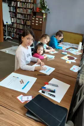 Dzieci kolorują przy stole.