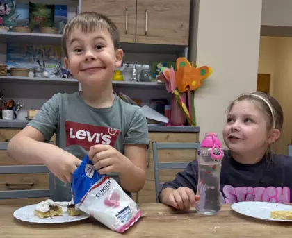 Dzieci jedzą gofry z bitą śmietaną i owocami