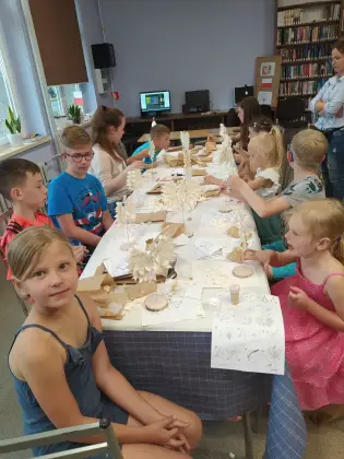 Uczestnicy spotkania oklejają statuetkę orła wiórkami osikowymi.