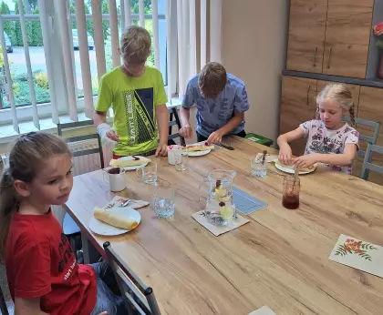 Dzieci ozdabiają naleśniki dżemem i nutellą.