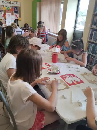 Uczestnicy zajęć malują farbami godło Polski.