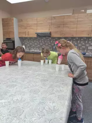 Dzieci bawią się w zabawę dmuchając balonik.