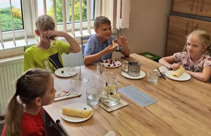 Uczestnicy zajęć jedzą naleśniki.