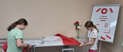 Dziewczyny szyją flagę Polski.