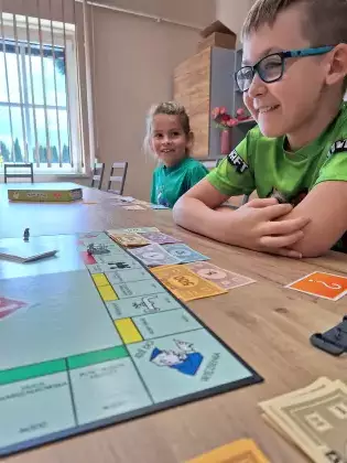 Chłopcy siedzą przy stole i grają w grę planszową.