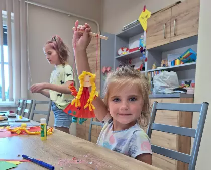 Dziewczynka bawi się zrobioną laleczką - marionetką.