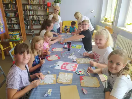 Uczestnicy warsztatów wyklejają masą plastyczną godło Polski.