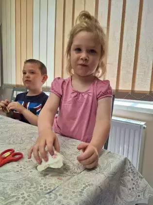 Dziewczynka i chłopczyk z kolorowego papieru wykonują parasol.