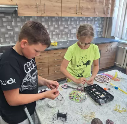 Chłopak i dziewczyna nawlekają koraliki.