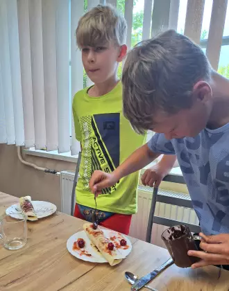 Chłopcy ozdabiają naleśniki.