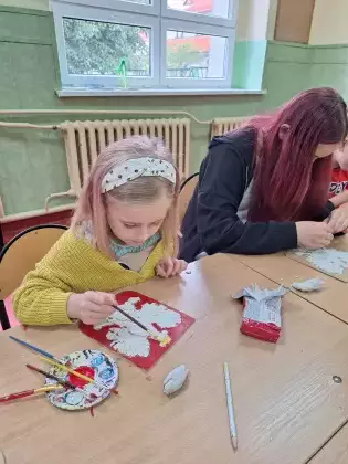 Dziewczyny malują farbami godło Polski.