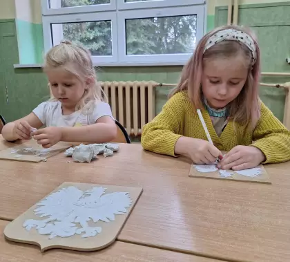 Dziewczynki wyklejają z masy modelarskiej postać orła białego.