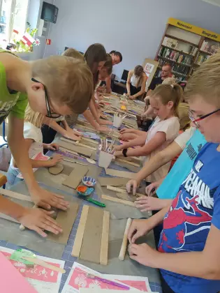 Uczestnicy spotkania wałkują glinę tworząc kubek ceramiczny.