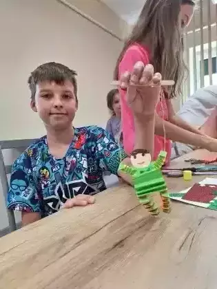 Chłopiec pokazuje zrobioną na zajęciach marionetkę.
