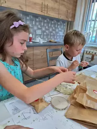 Chłopczyk i dziewczynka wykonują statuetkę orzełka.