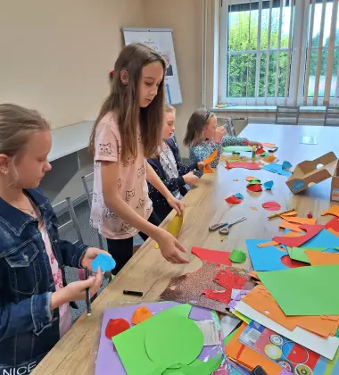 Uczestnicy zajęć wycinają z papieru rybki.