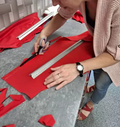 Uczestniczka warsztatów kroi materiał na koszulkę.
