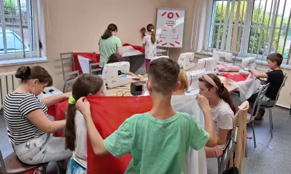 Dzieci szyją na maszynie flagę Polski.