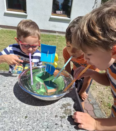 Chłopcy puszczają statki wykonane z gąbki do mycia naczyń.