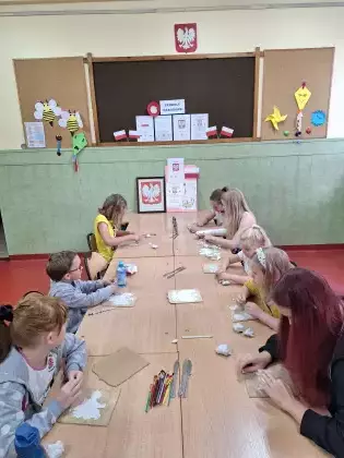 Uczestnicy warsztatów plastycznych wyklejają godło Polski.
 