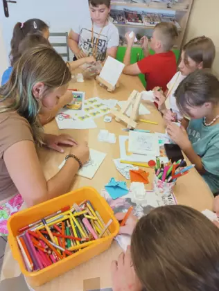 Dzieci kolorują kredkami obrazki.