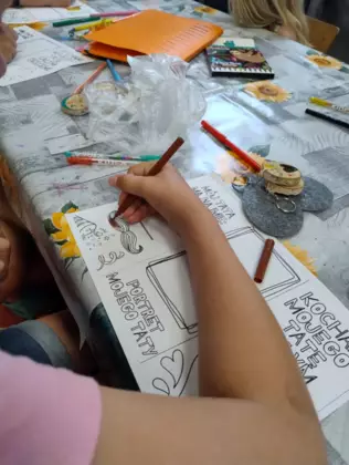 Dziewczynka pisze życzenia dla taty.