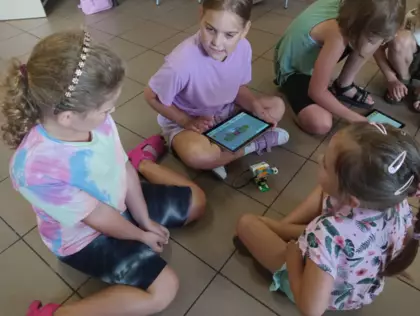 Dzieci tabletem sterują pojazd zbudowany z klocków lego.