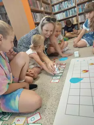 Pani prowadząca zajęcia pokazuje uczestnikom jak zaprogramować robota - Genibota.