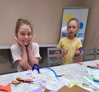 Dziewczynki wycinają motylki z papieru.