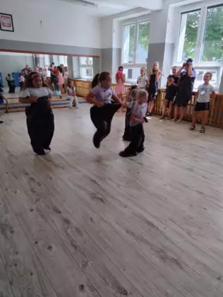 Dzieci skaczą w workach jak kangurki na sali gimnastycznej.
