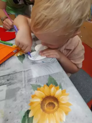 Chłopczyk na serduszku pisze życzenia dla taty.