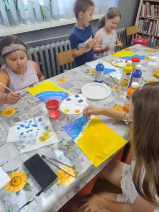 Dzieci malują farbami wakacyjne obrazki.