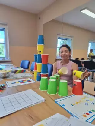 Dziewczyna układa wieżę z kubków według podanego schematu