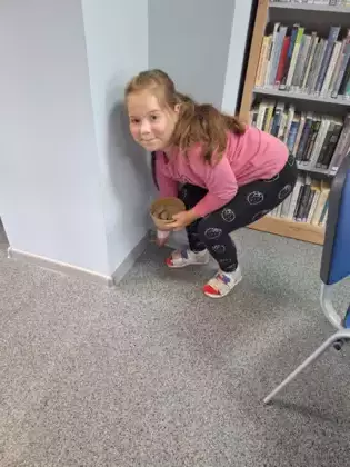 Dziewczynka znalazła kamień i podnosi go z podłogi.